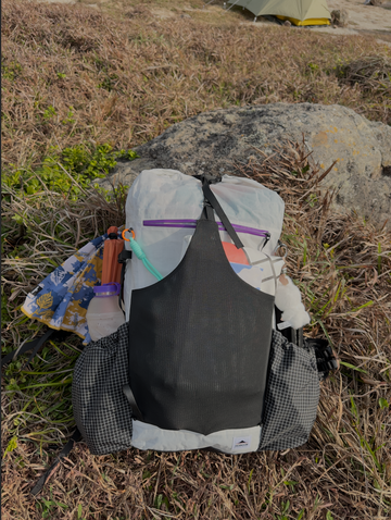 Packed 40L hiking backpack with exterior pockets at a campsite