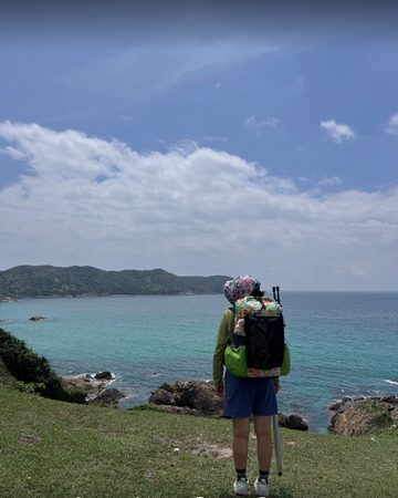 Hiker wearing a floral-print OCE GEAR 40L Dyneema DCH ultralight backpack on a coastal trail