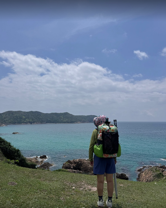 Hiker wearing a floral-print OCE GEAR 40L Dyneema DCH ultralight backpack on a coastal trail