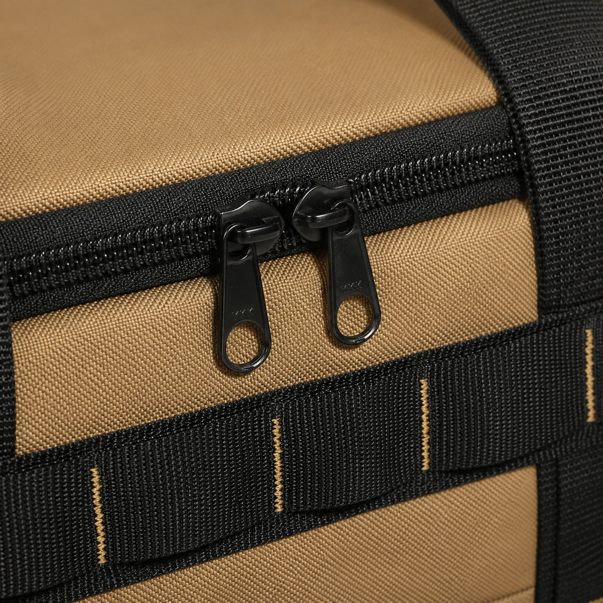 Close-up of dual black zipper pulls on khaki camping organizer bag