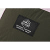 Close-up of black OCE GEAR logo patch on dark olive ripstop-textured fabric