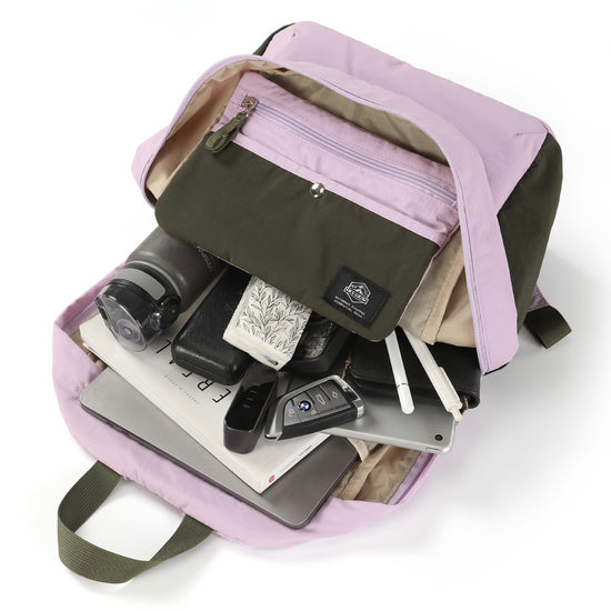 Open backpack with daily carry items, front organizer pouch, and beige lining visible