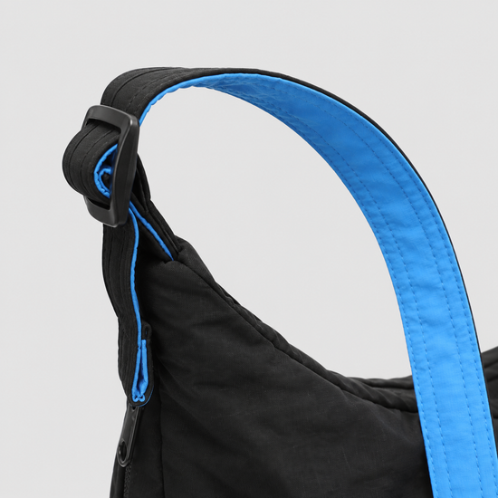 Shoulder strap and side zipper detail on expandable crescent bag